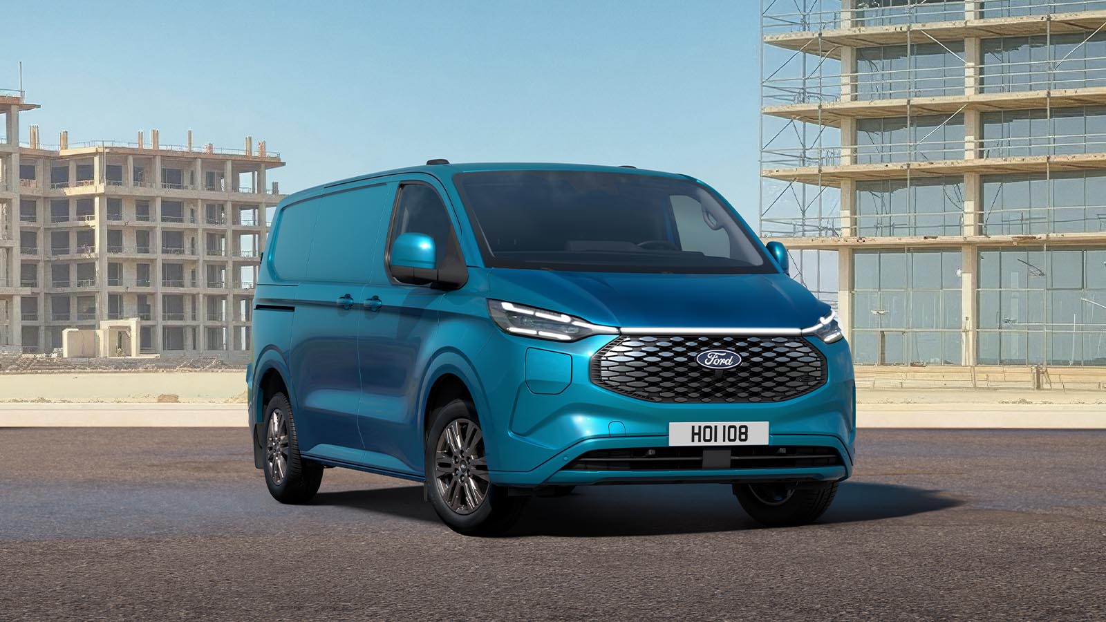 Ford E-Transit Custom in Blau. Dreiviertelansicht, parkt auf einer Baustelle.