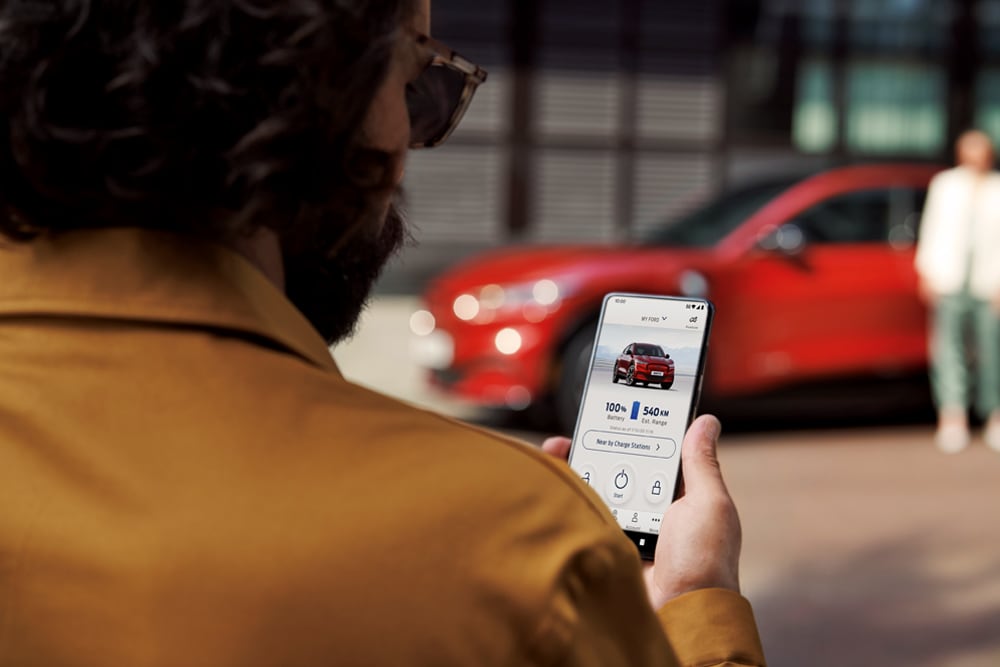 FordPass. Mann prüft den Ladestand seines Ford Mustang Mach-E über die FordPass App