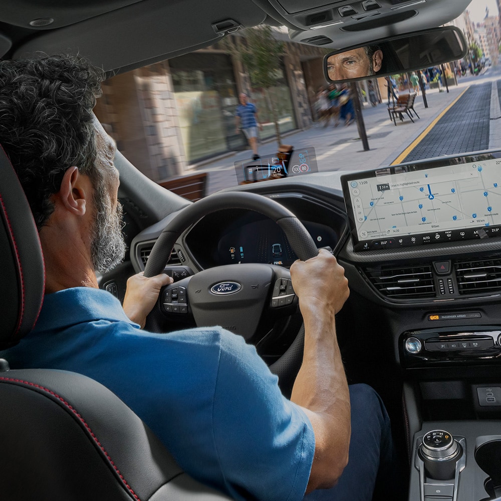 Ford Kuga Innenraum. Ansicht auf Lenkrad und Armaturenbrett mit Ford SYNC 4-Touchscreen. Mann sitzt im Fahrersitz.