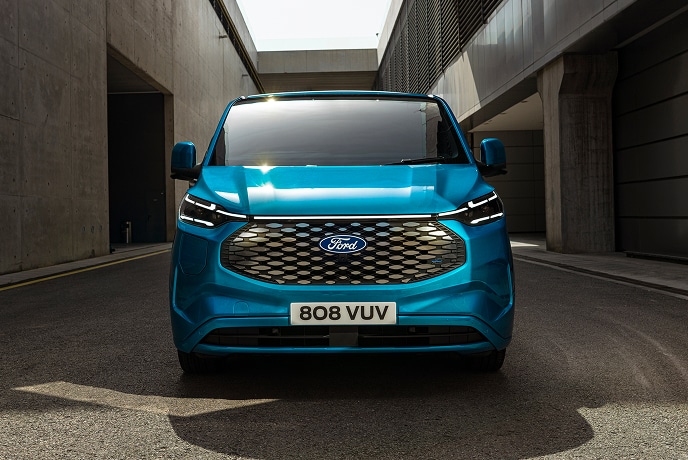 Ford E-Transit Custom in Blau. Frontansicht, parkt in einer Gasse.